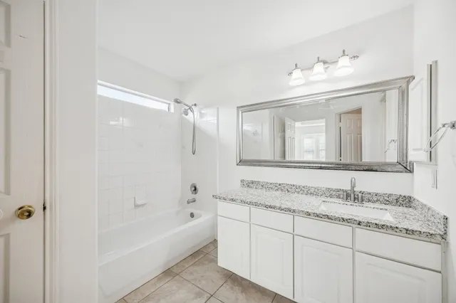 a bathroom with a granite countertop sink mirror and bathtub
