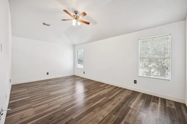 a view of a room with wooden floor and a ceiling fan