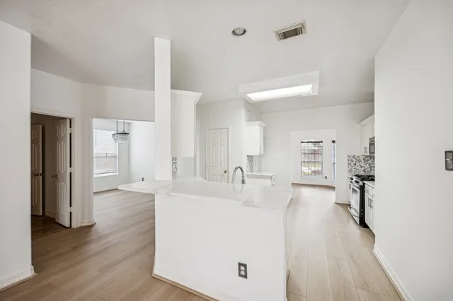 a large white kitchen with wooden floor