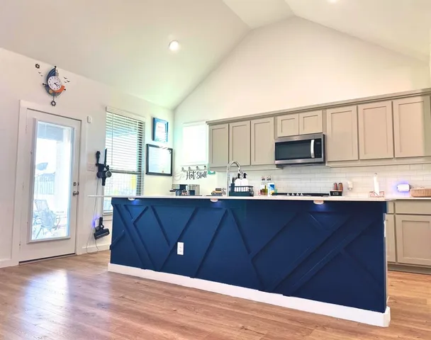 a kitchen with stainless steel appliances granite countertop wooden cabinets a stove top oven a sink and dishwasher with wooden floor