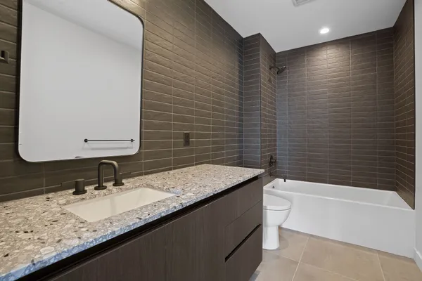 a bathroom with a granite countertop sink a toilet and bathtub