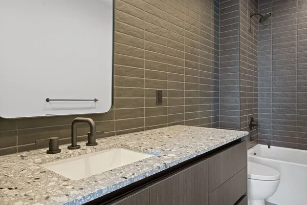 a bathroom with a granite countertop sink a toilet and mirror