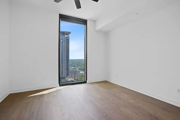 an empty room with wooden floor and windows