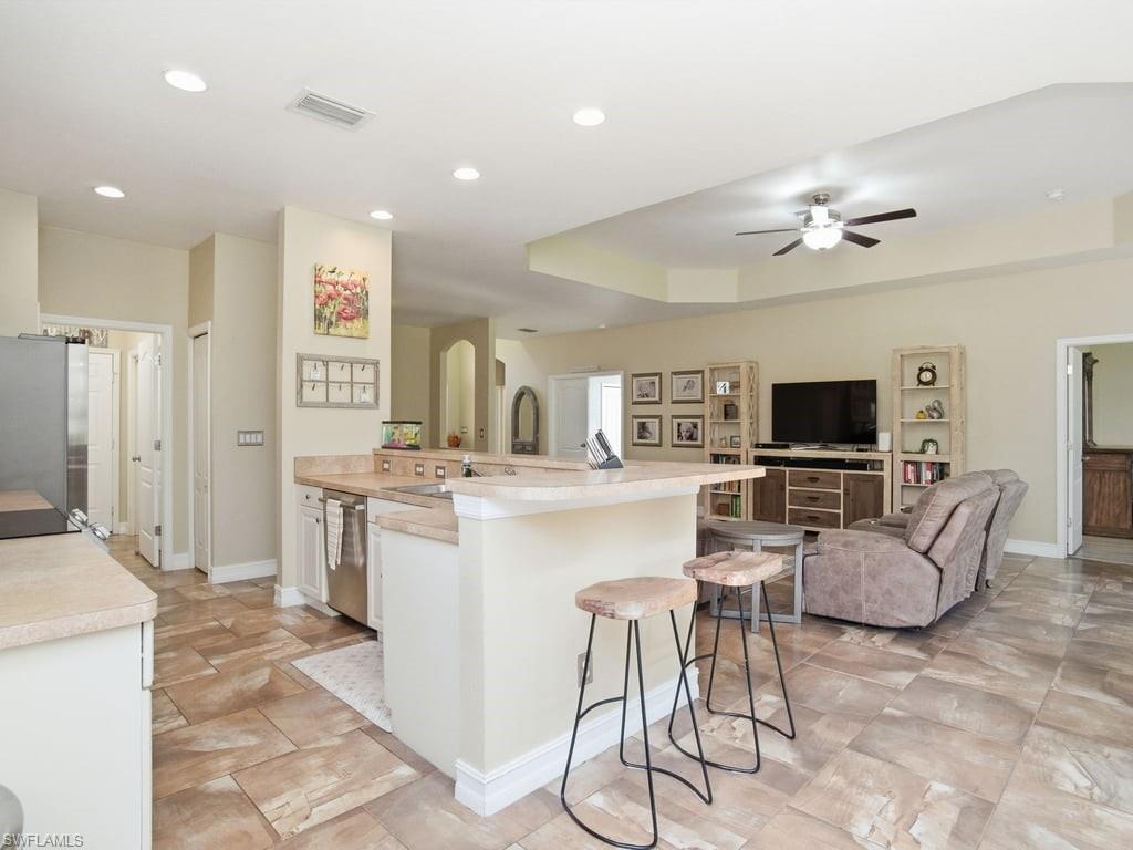 12719 Stone Tower Loop Fort Myers, FL 33913 - Photo 13 of 45 a living room with furniture a flat screen tv and kitchen view