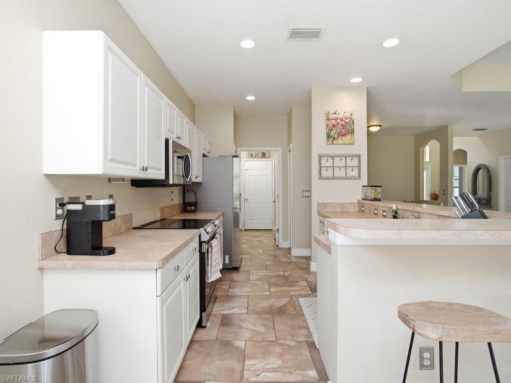 12719 Stone Tower Loop Fort Myers, FL 33913 - Photo 14 of 45 a kitchen with kitchen island a sink appliances and cabinets