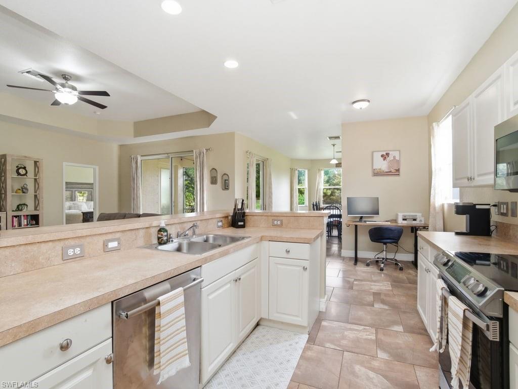 12719 Stone Tower Loop Fort Myers, FL 33913 - Photo 18 of 45 a large white kitchen with a sink and dishwasher a stove top oven with wooden floor