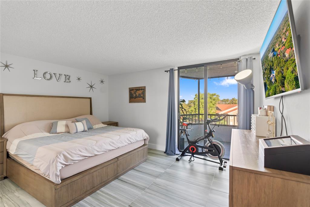 1850 Homewood Boulevard, Unit 512 Delray Beach, FL 33445 - Photo 17 of 43 a bedroom with a bed and a flat tv screen on the dresser