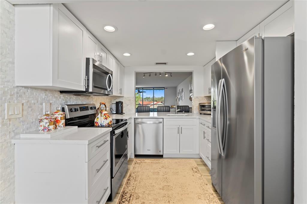 1850 Homewood Boulevard, Unit 512 Delray Beach, FL 33445 - Photo 9 of 43 a kitchen with white cabinets and stainless steel appliances