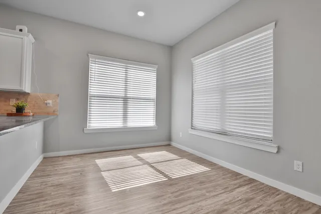 a view of an empty room with a window and wooden floor