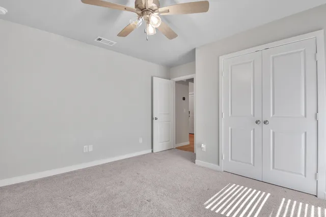 a view of an empty room and chandelier fan