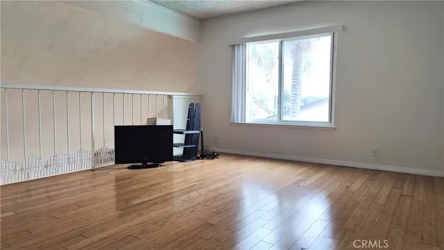 an empty room with wooden floor fireplace and windows
