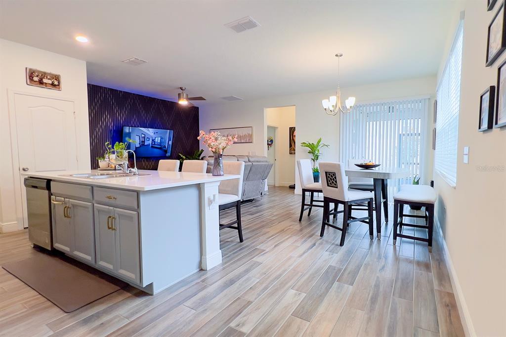 2755 Mdw Strm Way Clermont, FL 34714 - Photo 14 of 64 a kitchen with a table chairs wooden floors and white stainless steel appliances