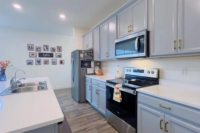 a kitchen with stainless steel appliances granite countertop a refrigerator a stove a sink dishwasher and a dining table with wooden floor