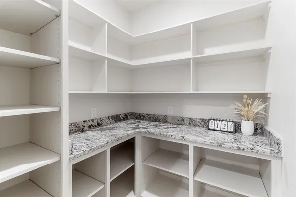 a bathroom with a granite countertop sink a mirror a potted plant and a shower