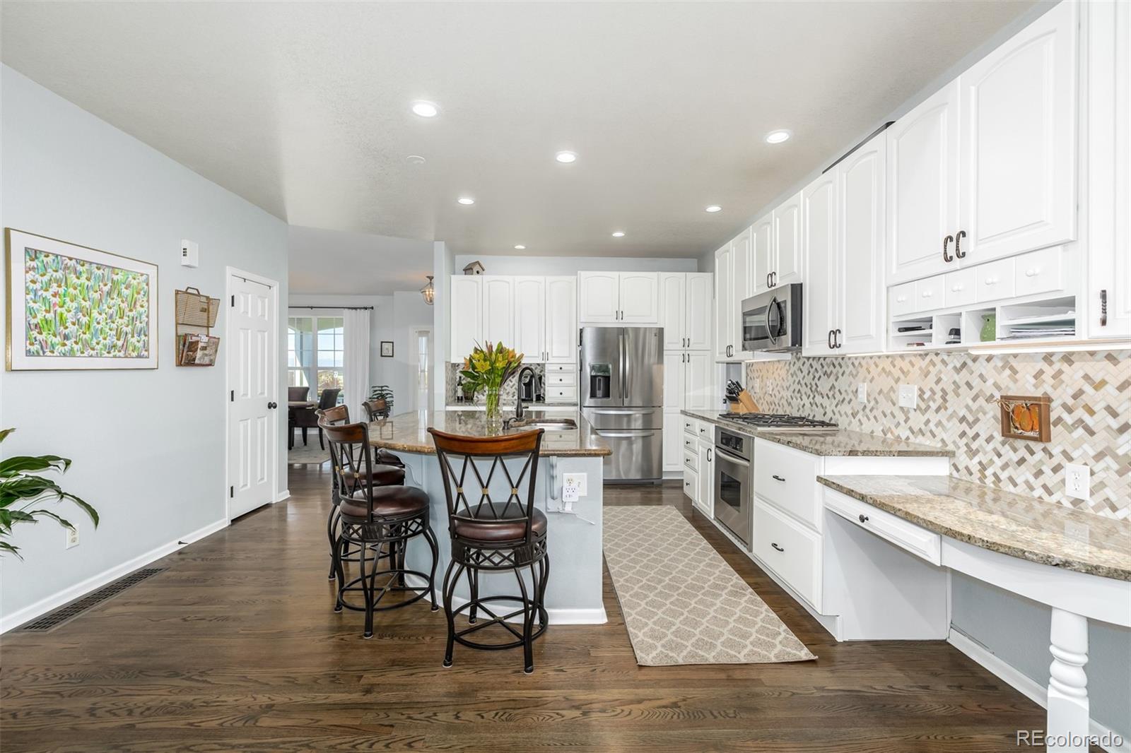 14704 Eagle River Loop Broomfield, CO 80023 - Photo 11 of 30 a kitchen with stainless steel appliances kitchen island granite countertop a table chairs sink and cabinets