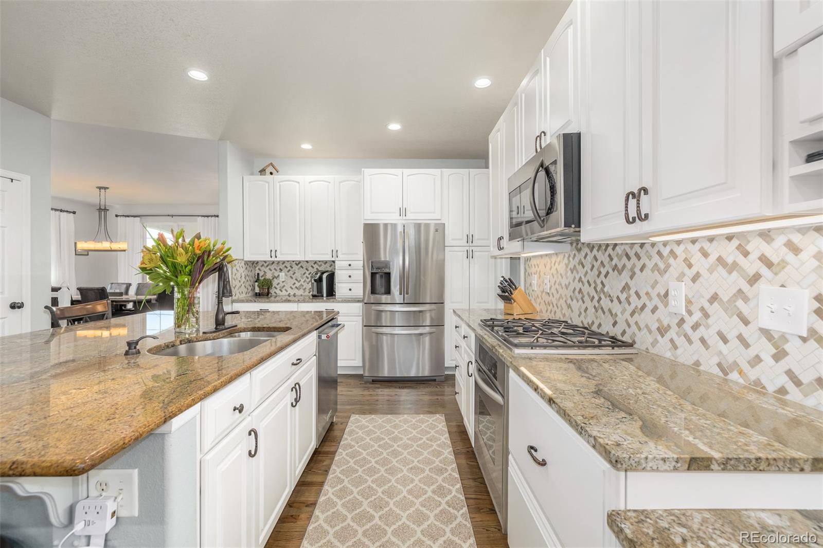 14704 Eagle River Loop Broomfield, CO 80023 - Photo 12 of 30 a kitchen with stainless steel appliances granite countertop a sink a stove and a refrigerator