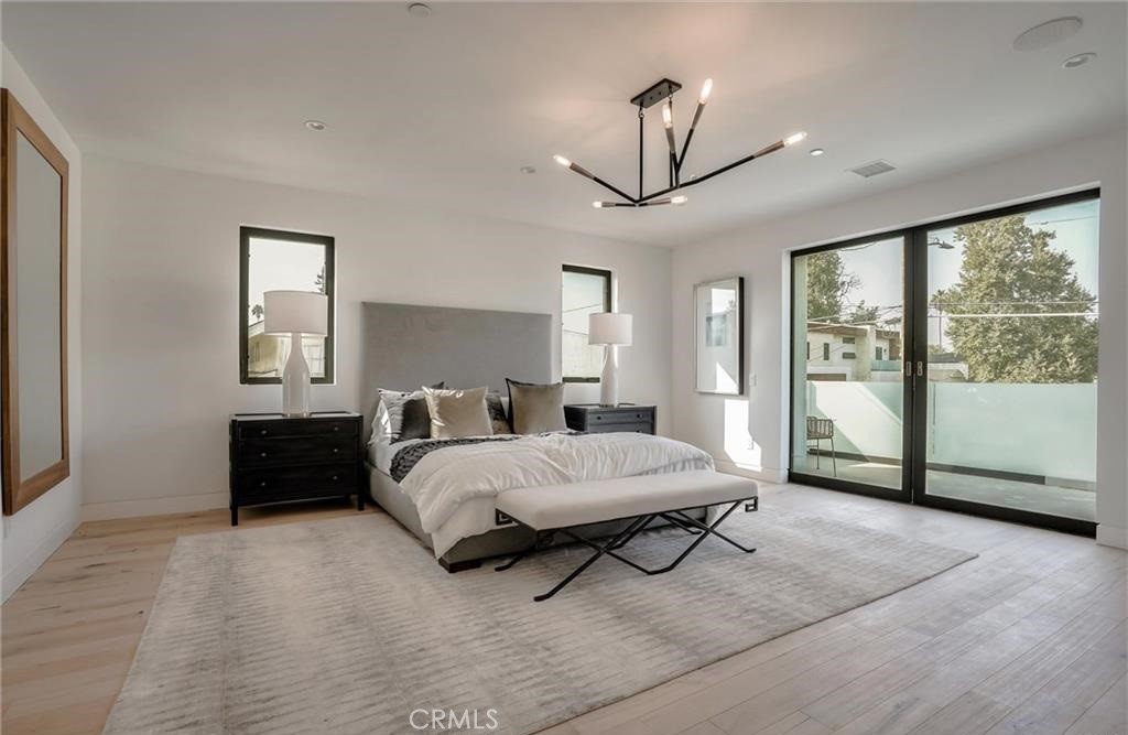 15926 Morrison Street Encino, CA 91436 - Photo 35 of 67 a spacious bedroom with a bed a chandelier and windows