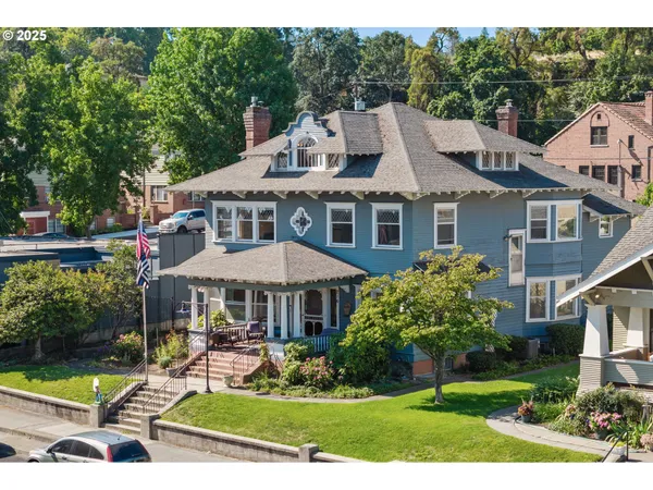 a view of a white house with a yard chairs and table in a patio