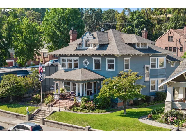 a view of a white house with a yard chairs and table in a patio