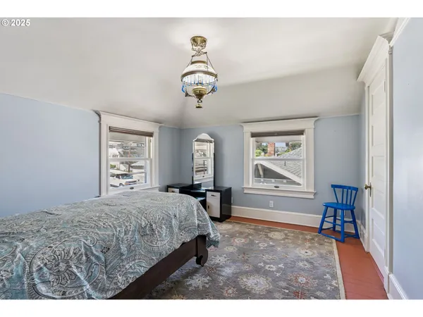 a bedroom with a bed next to a window and a chandelier