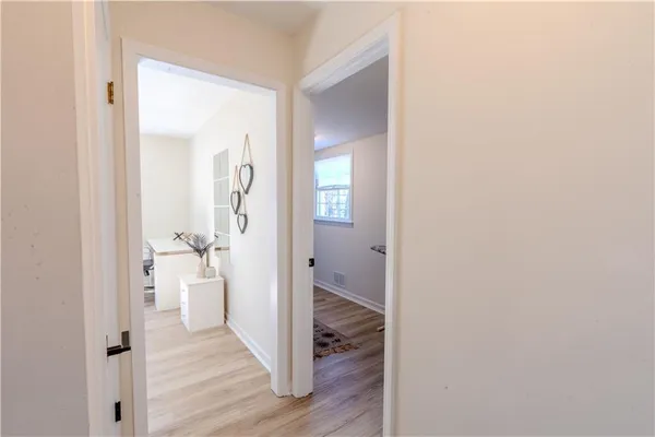 a view of a hallway with wooden floor and a bathroom
