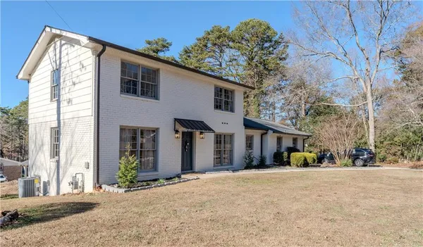 a view of a white house with a large tree