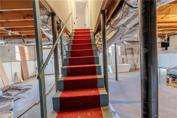 a view of staircase with lots of frames on wall and a large window
