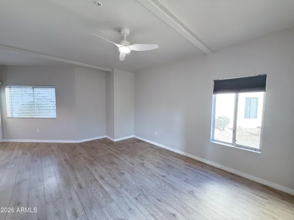 an empty room with wooden floor windows and fan