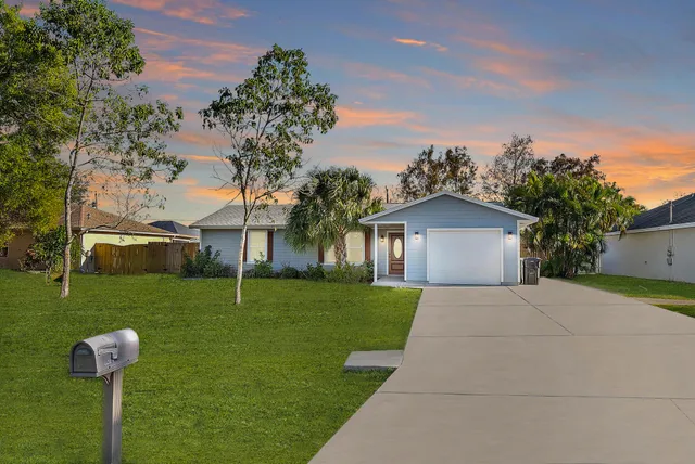 a front view of a house with a yard and tree