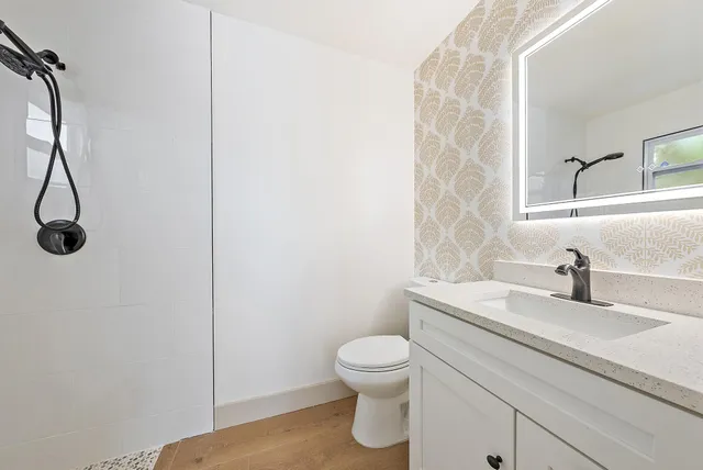 a bathroom with a granite countertop sink a toilet and a mirror