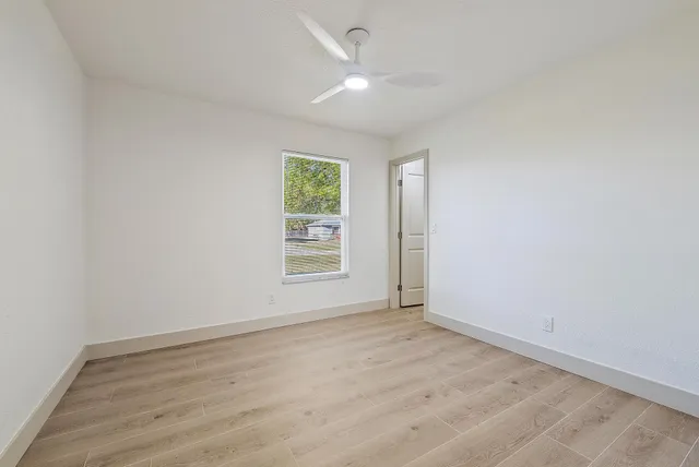 an empty room with a window and a ceiling fan
