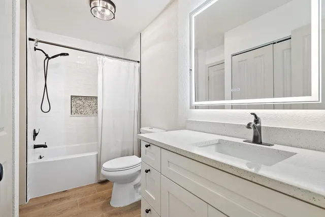 a bathroom with a granite countertop sink a toilet and shower