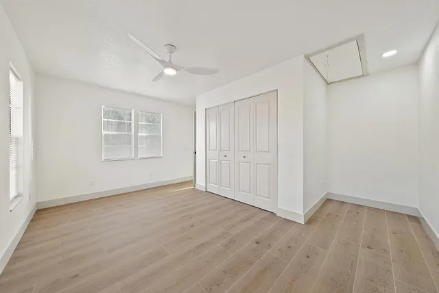 an empty room with wooden floor cabinet and windows