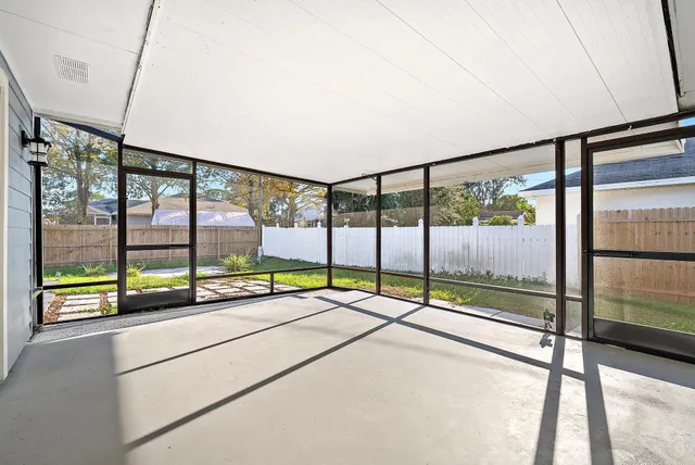 a view of an empty room with wooden floor and windows