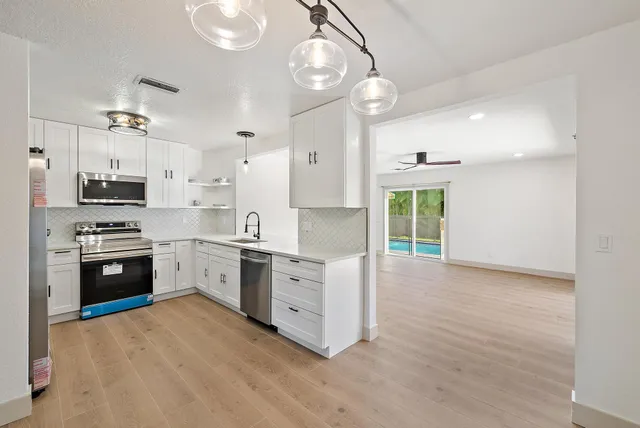 a kitchen with stainless steel appliances kitchen island granite countertop a stove a sink a refrigerator and a white cabinets