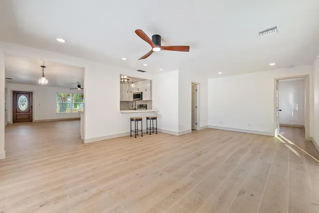 a view of an empty room with window and wooden floor