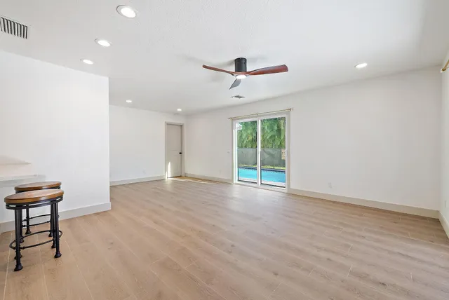a view of an empty room with a window and wooden floor