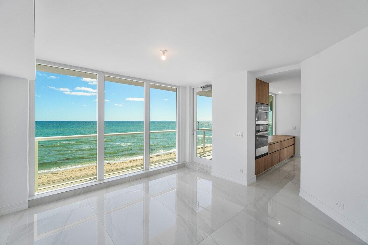 3505 South Ocean Boulevard, Unit 4S Highland Beach, FL 33487 - Photo 20 of 48 an empty room with floor to ceiling windows and kitchen view