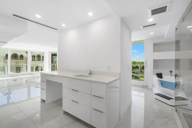 a large white kitchen with a sink and dishwasher with a large window