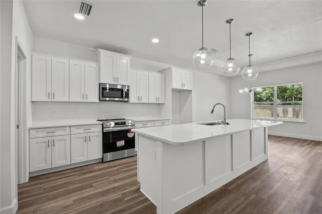 a kitchen with kitchen island granite countertop a sink stainless steel appliances and white cabinets