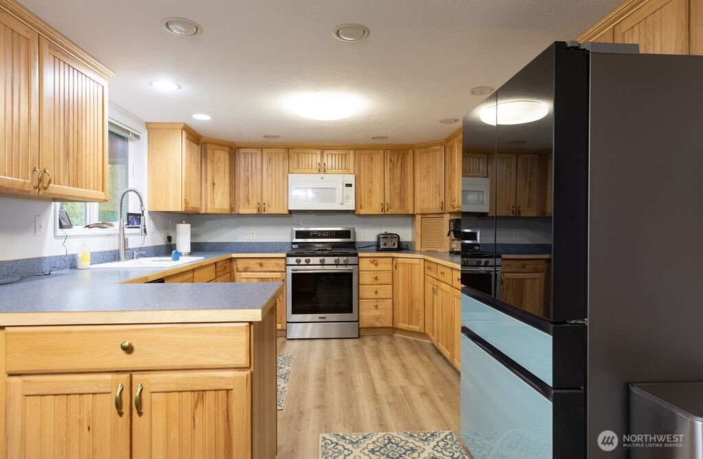 194 Sekiu Airport Road Sekiu, WA 98381 - Photo 6 of 40 a kitchen with granite countertop a stove a sink and a refrigerator