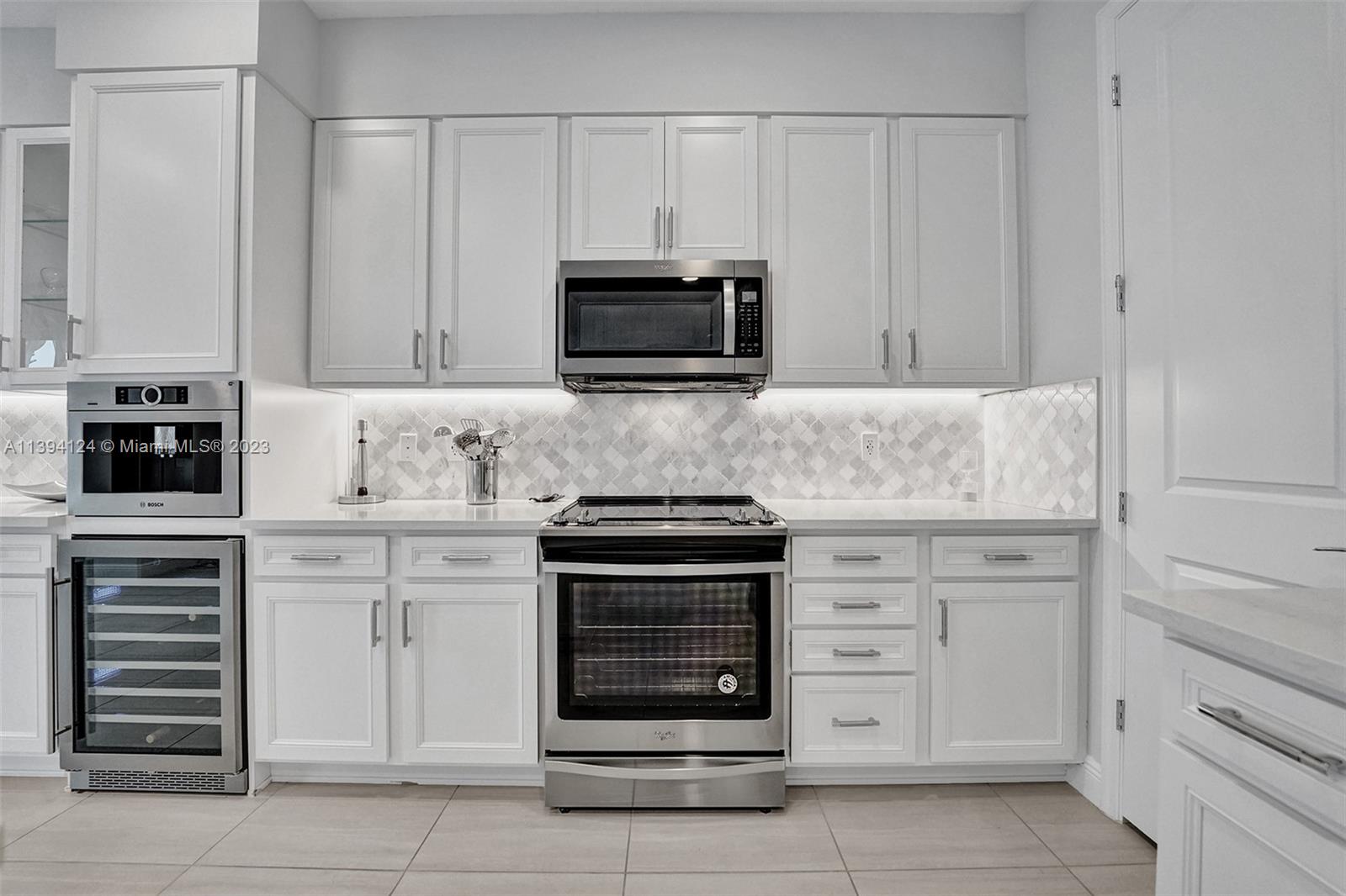 1033 Eucalyptus Drive Hollywood, FL 33021 - Photo 10 of 66 a kitchen with white cabinets and stainless steel appliances