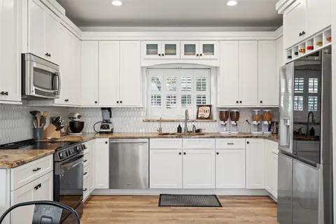 a kitchen with granite countertop cabinets stainless steel appliances a sink and a window