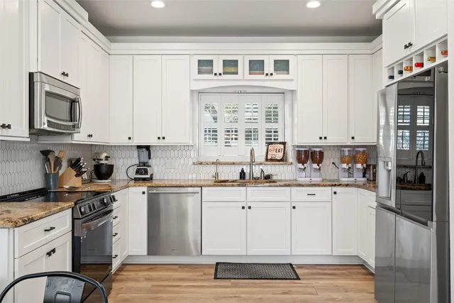 a kitchen with granite countertop cabinets stainless steel appliances a sink and a window