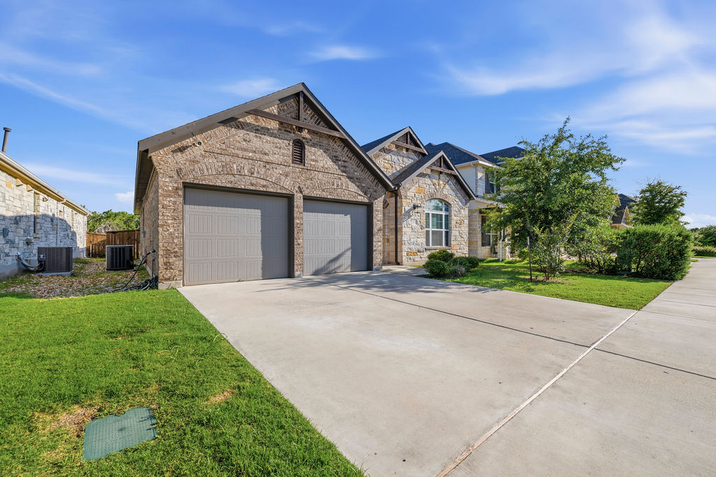 2032 Base Burner Path Leander, TX 78641 - Photo 2 of 34 Front exterior showcasing a two-car garage with overhead doors and a stone and brick facade