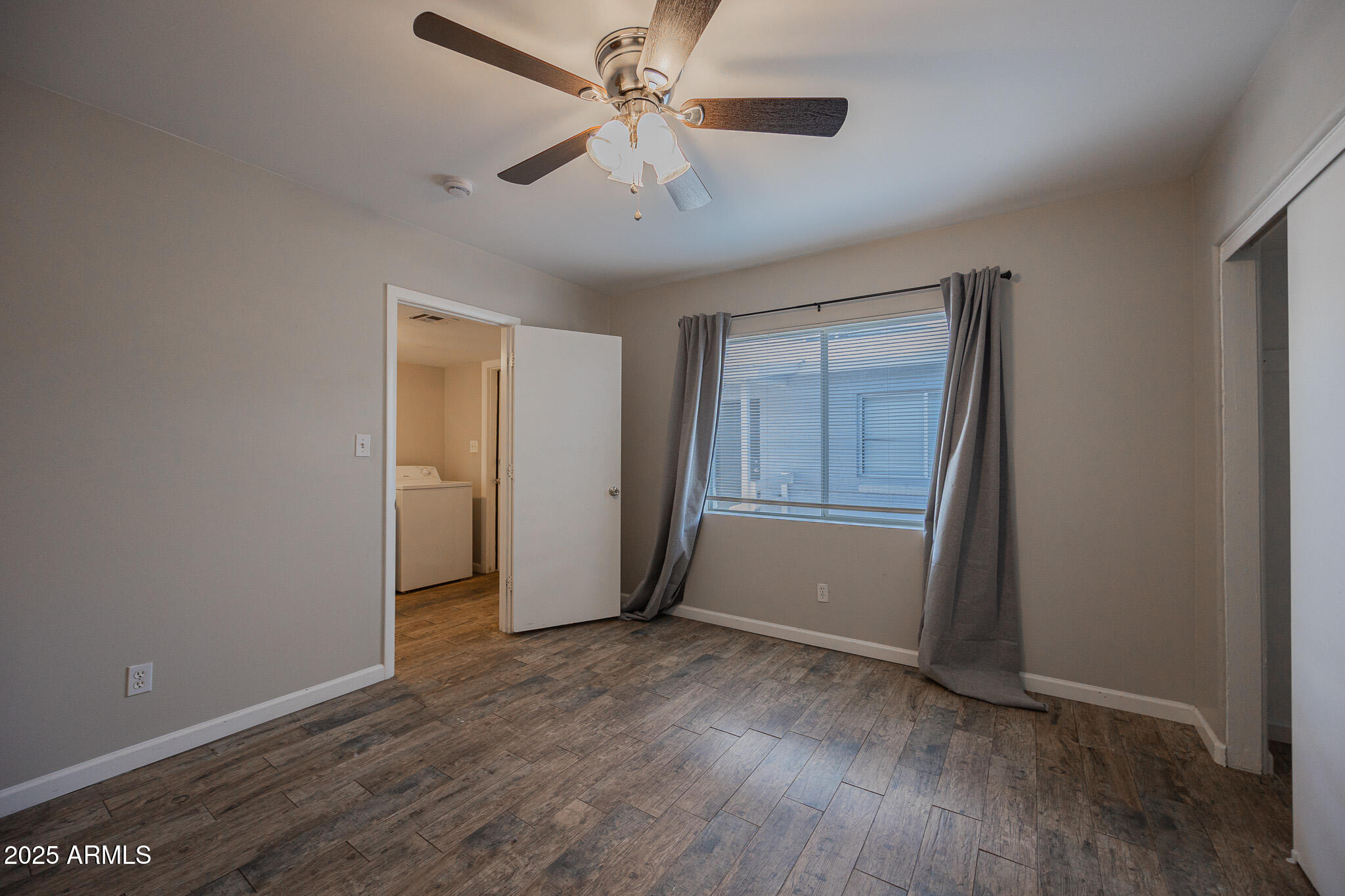 1507 East Harvard Street, Unit A Phoenix, AZ 85006 - Photo 12 of 14 an empty room with wooden floor chandelier fan and windows