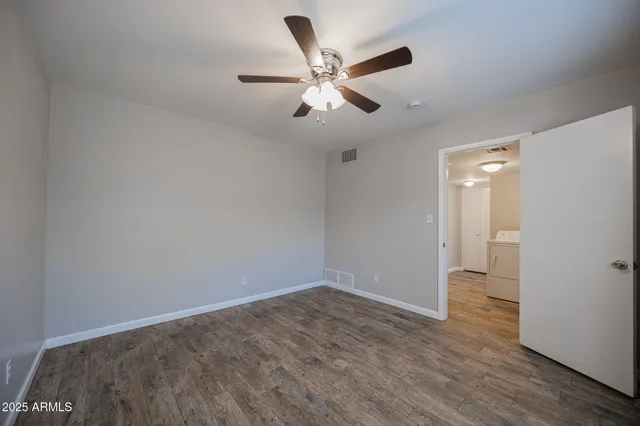 an empty room with closet and a ceiling fan