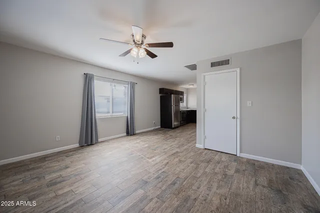 a view of empty room with wooden floor and ceiling fan