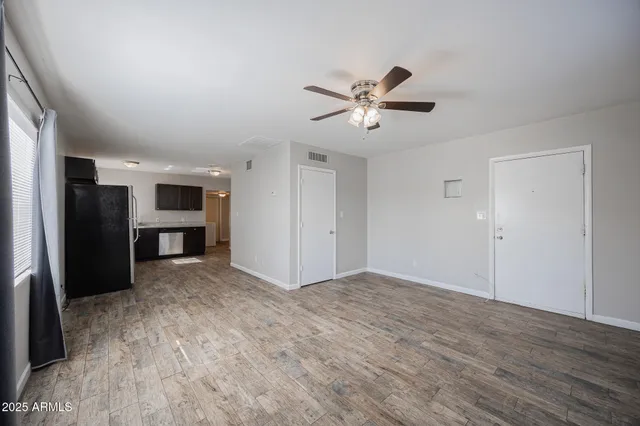 a view of empty room with wooden floor and ceiling fan