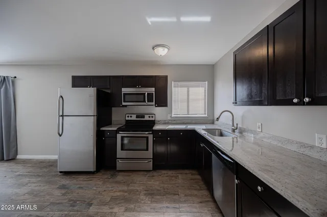 a kitchen with stainless steel appliances granite countertop a refrigerator a sink a stove a microwave and wooden cabinets